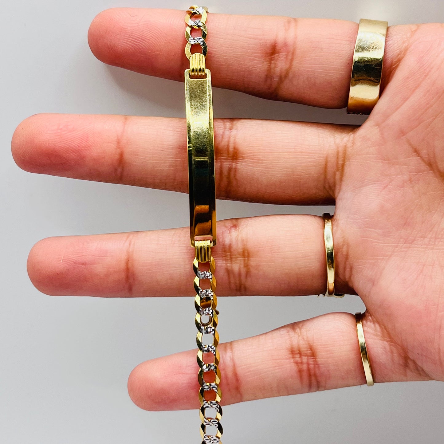 A person's hand displaying a 14k gold ID bracelet with a diamond cut solid 3mm Cuban link and a lobster clasp.