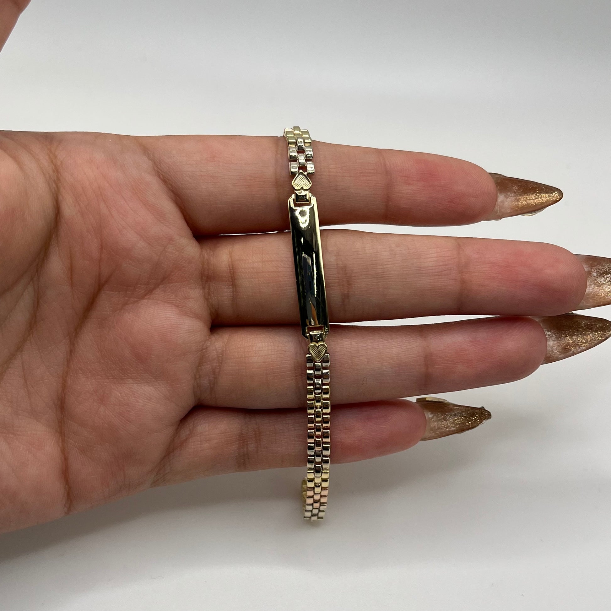 Gold bracelet on a hand against a white background