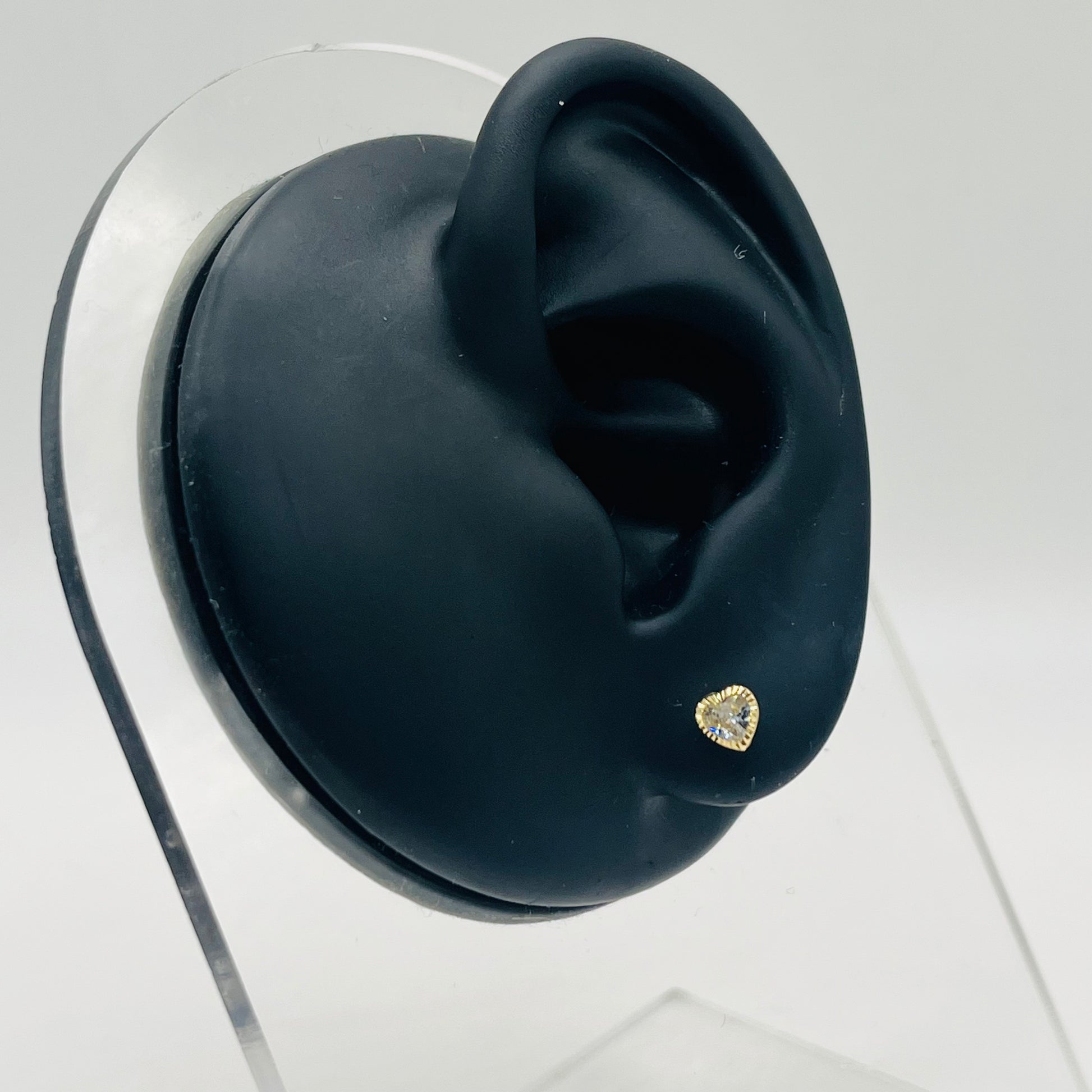 Black ear with a gold earring on a white background