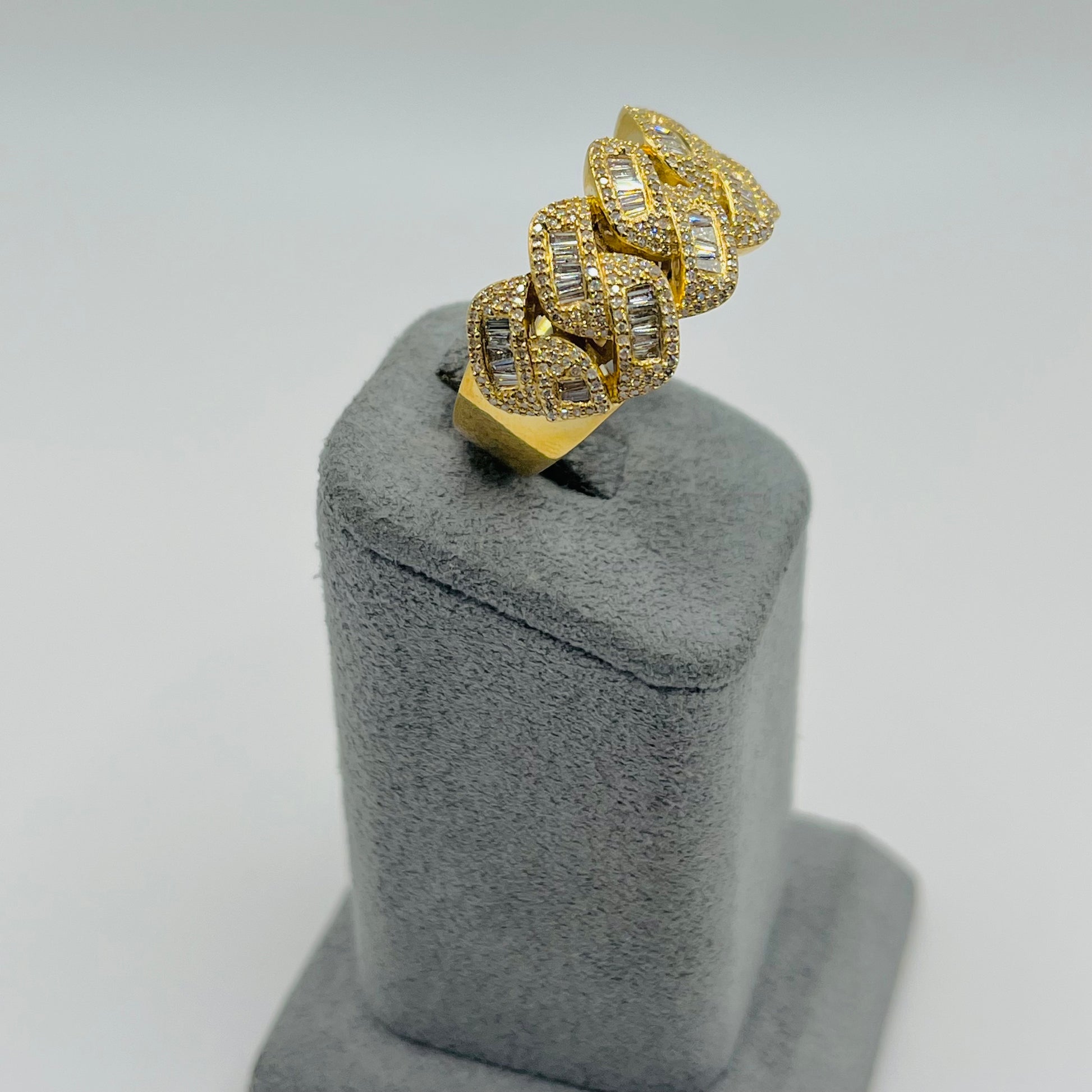 Gold ring with diamond accents on a gray stand against a light gray background