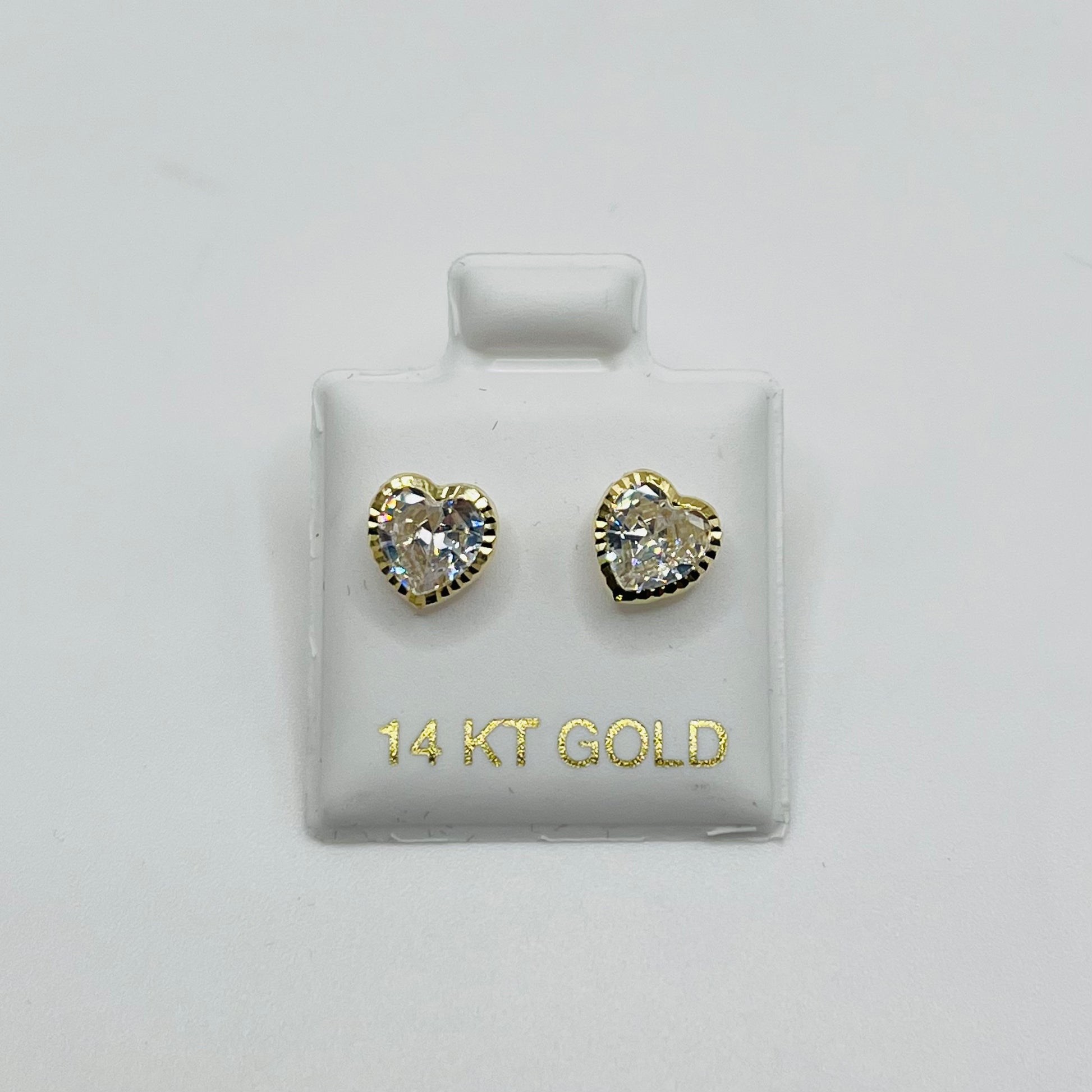 Heart-shaped gold earrings on a display card with '14 KT GOLD' text.