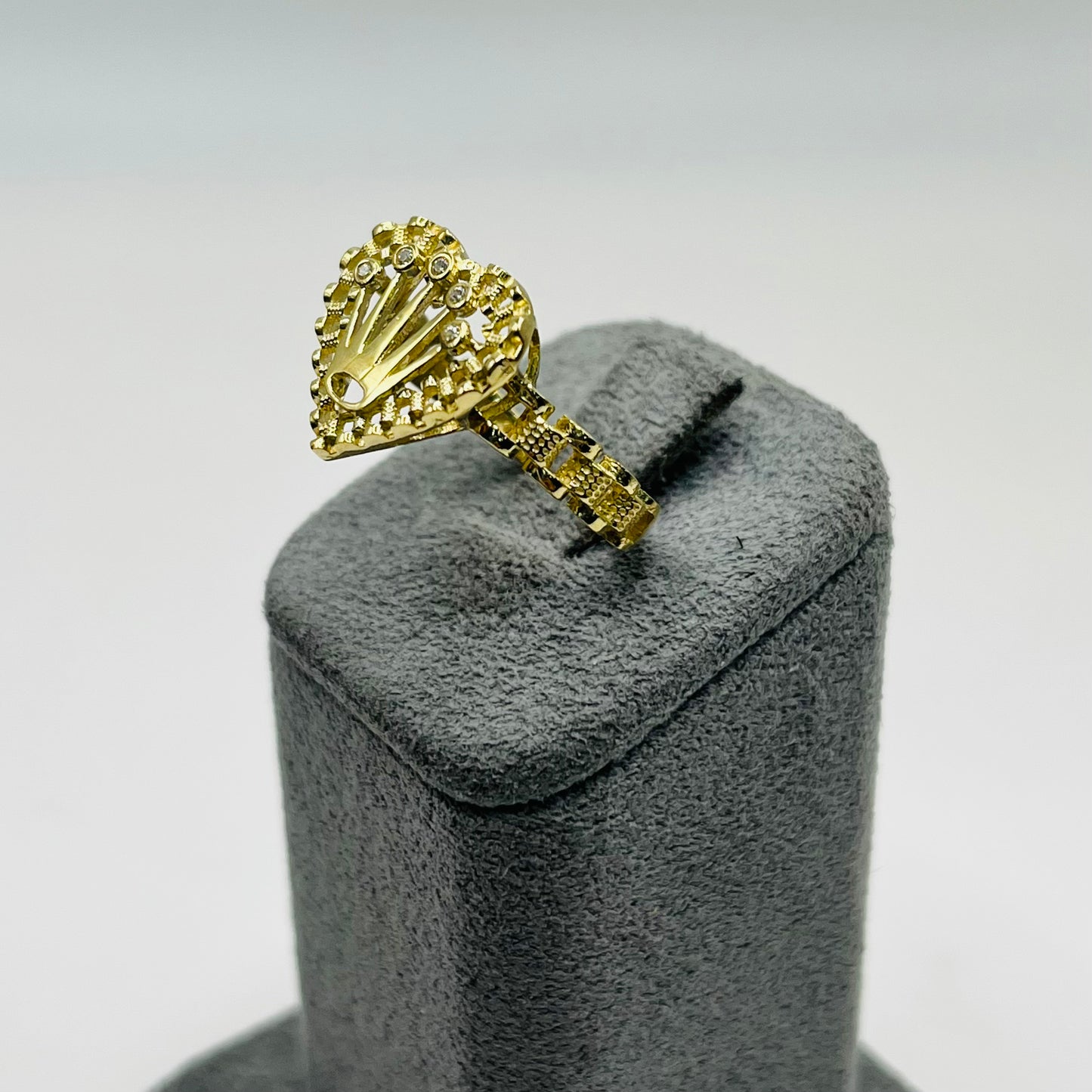 Gold ring on a gray velvet stand against a light gray background