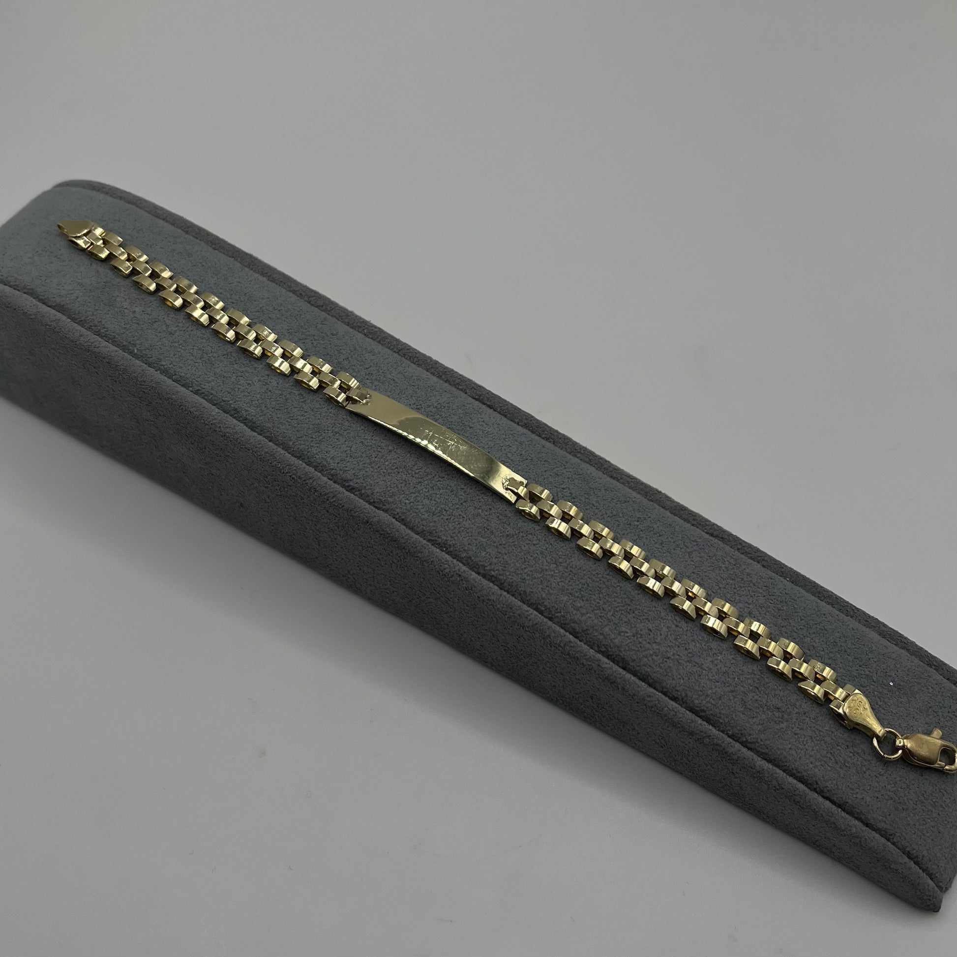 Gold chain bracelet in a gray box on a gray background