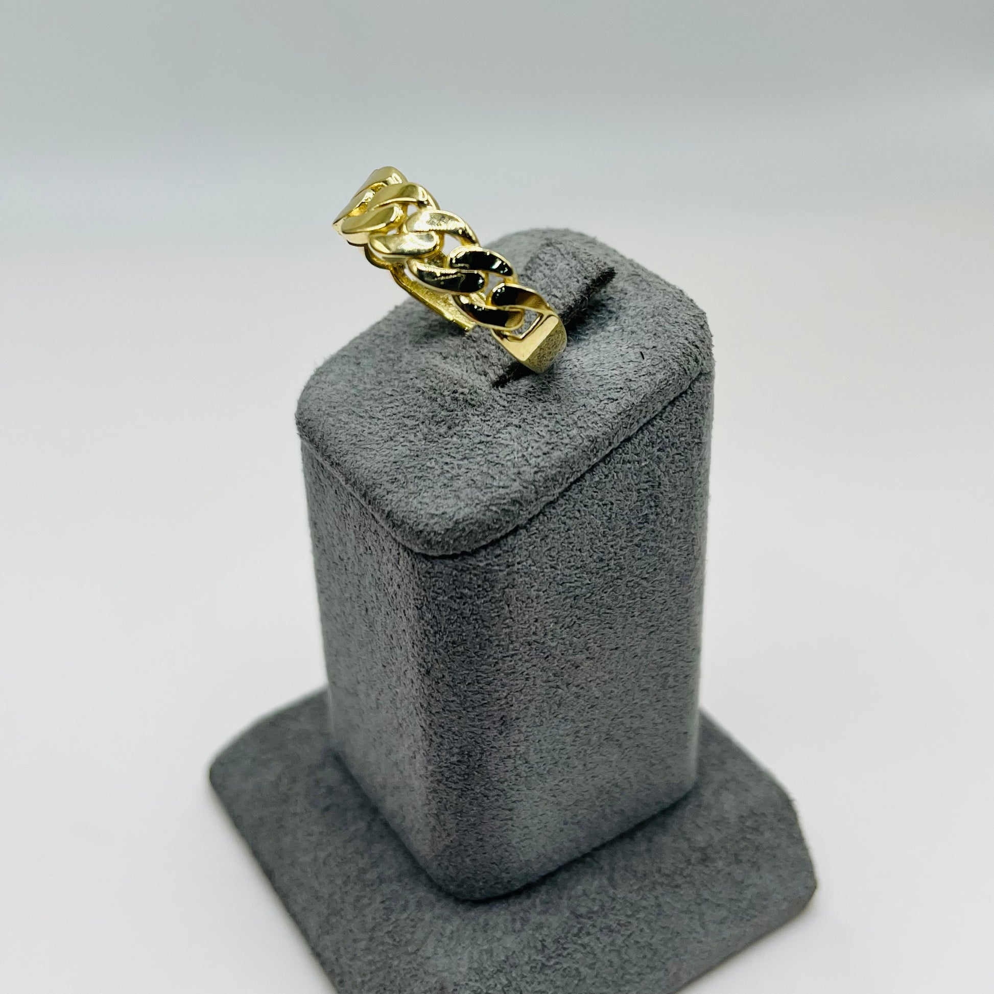 Gold ring on a gray jewelry display stand against a white background
