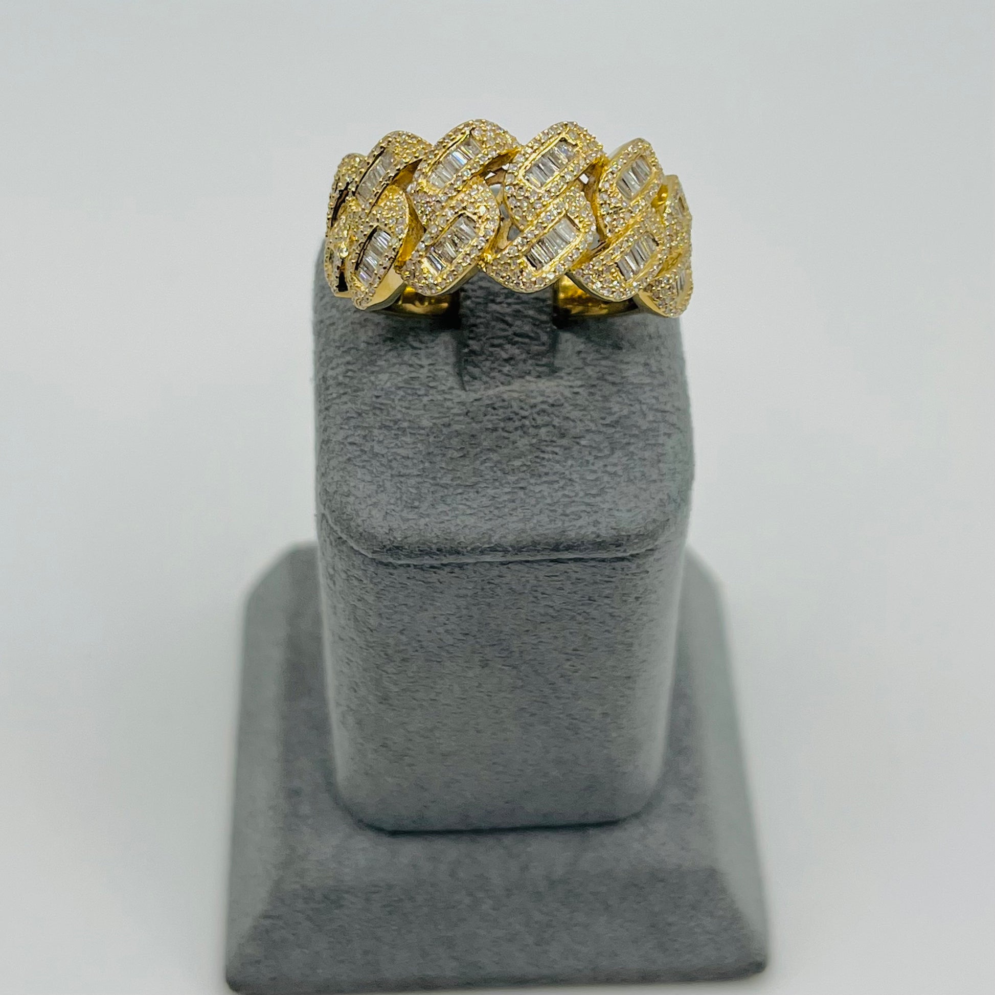 Gold ring with diamond accents on a gray stand against a light gray background
