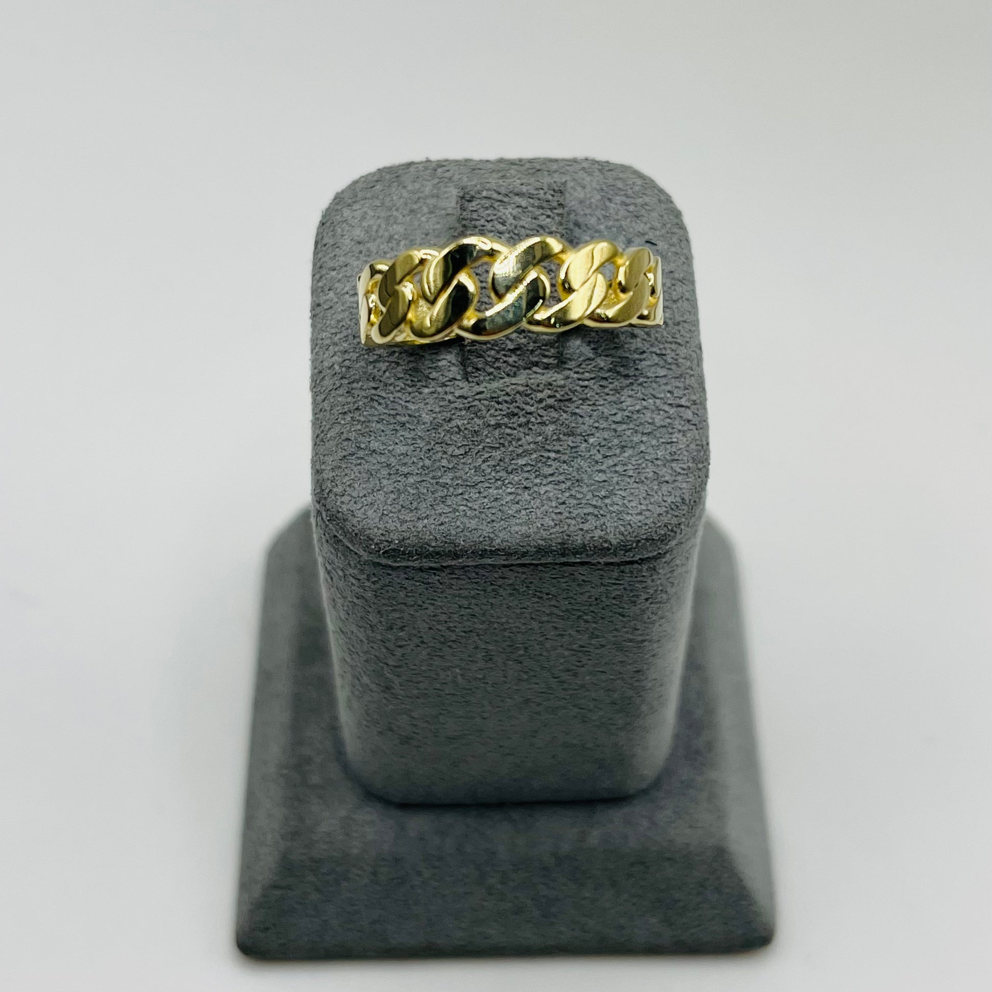 Gold chain ring on a gray stand with a light gray background