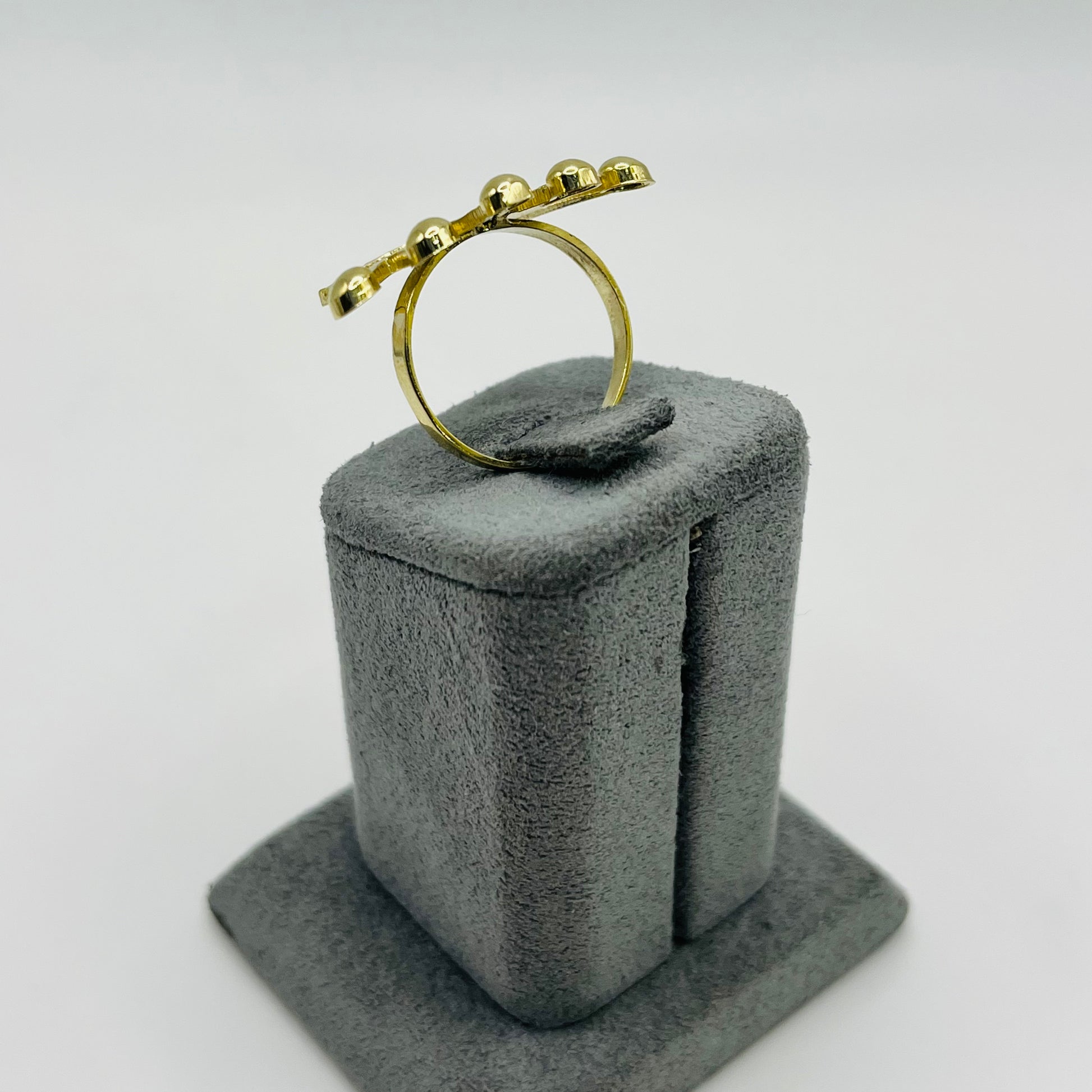 Gold ring on a gray cushioned stand against a white background
