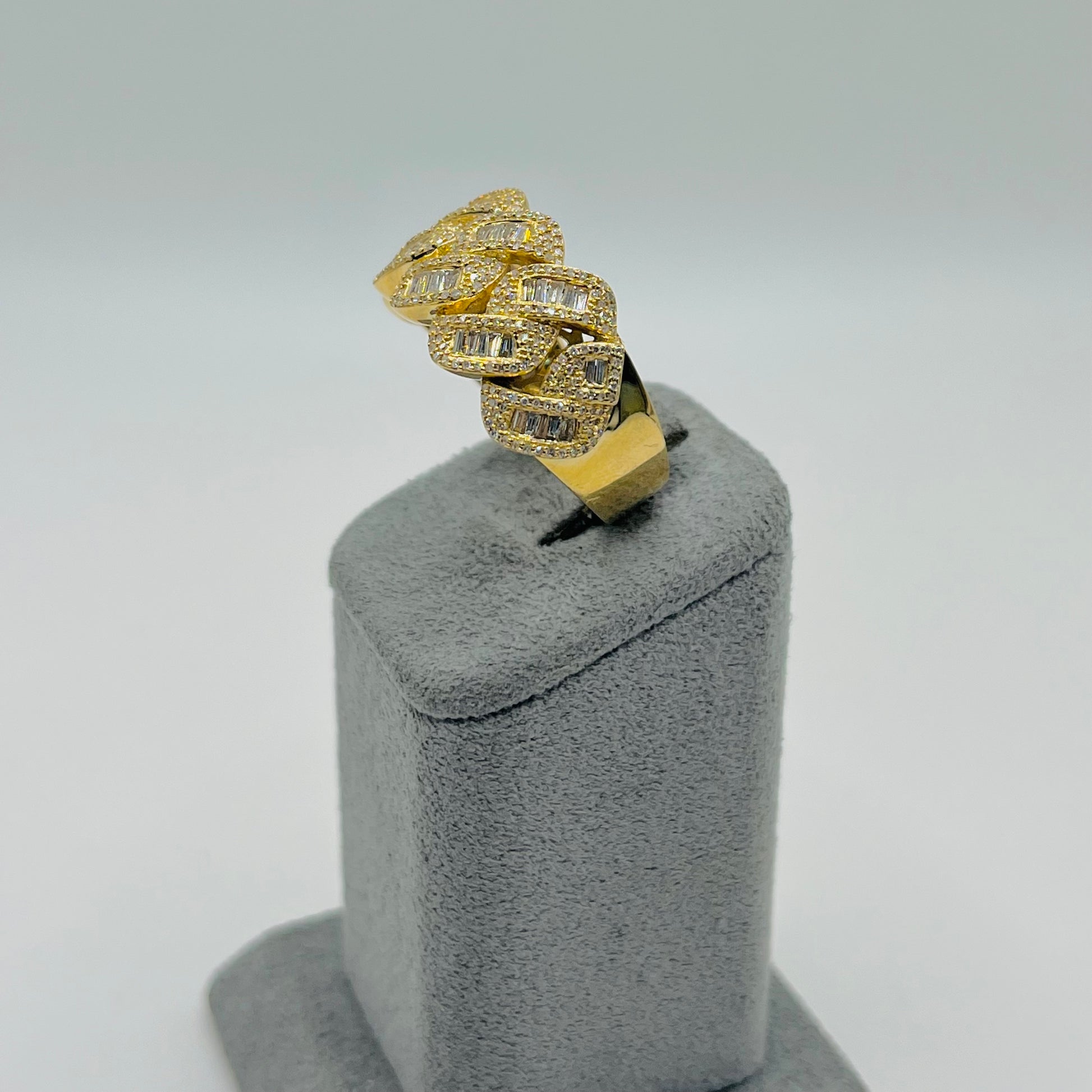 Gold ring with diamond accents on a gray stand against a light gray background