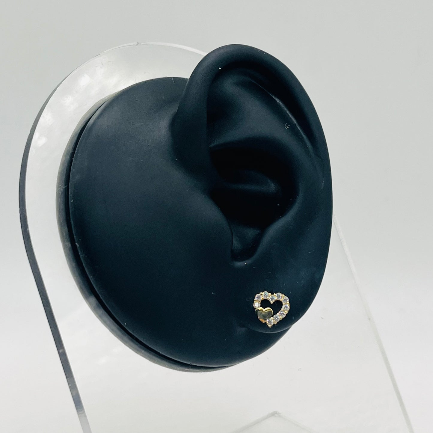 Heart-shaped earring on a black ear with a clear background