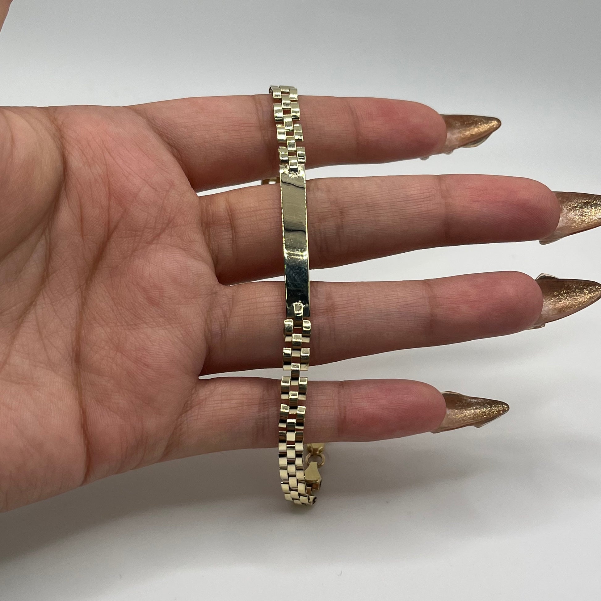 Gold bracelet on a person's wrist with a plain background