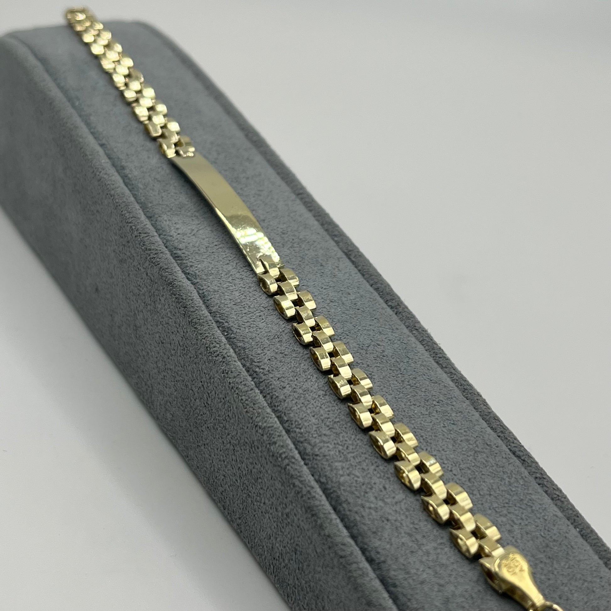 Gold chain bracelet on a gray cushioned surface
