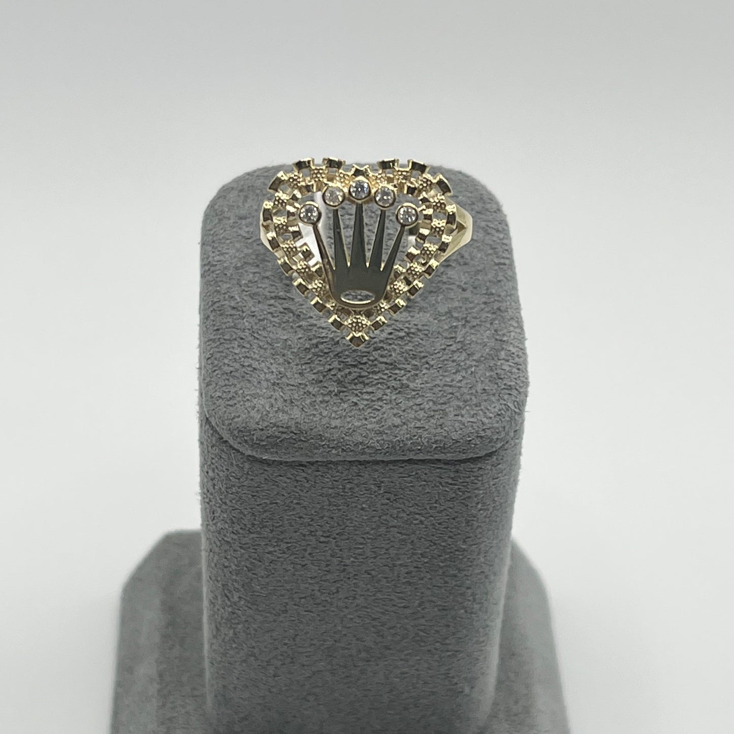 A 10K gold heart-shaped ring with a crown design on top, displayed on a grey stand.