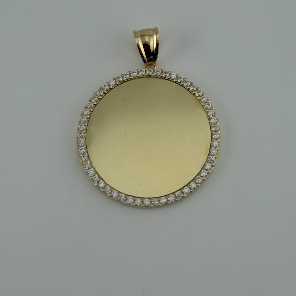 Gold pendant with a round face and diamond accents on a gray background