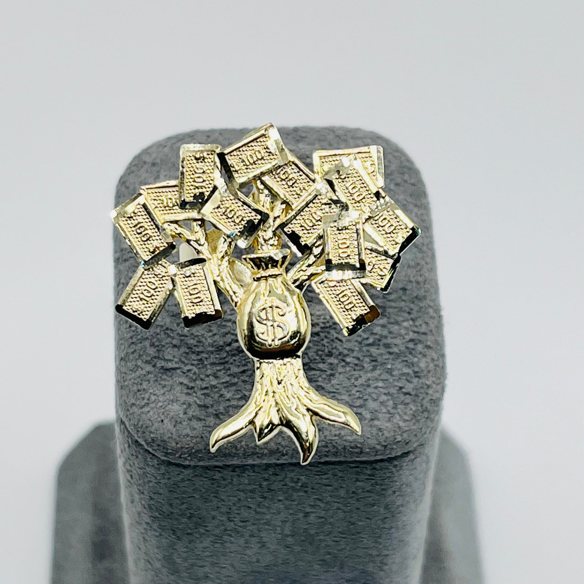 A 10K gold ring with a tree design featuring multiple branches and leaves, displayed on a grey mount.