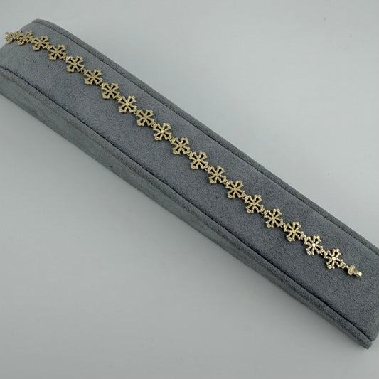 Gold bracelet on a gray velvet cushion with a light gray background