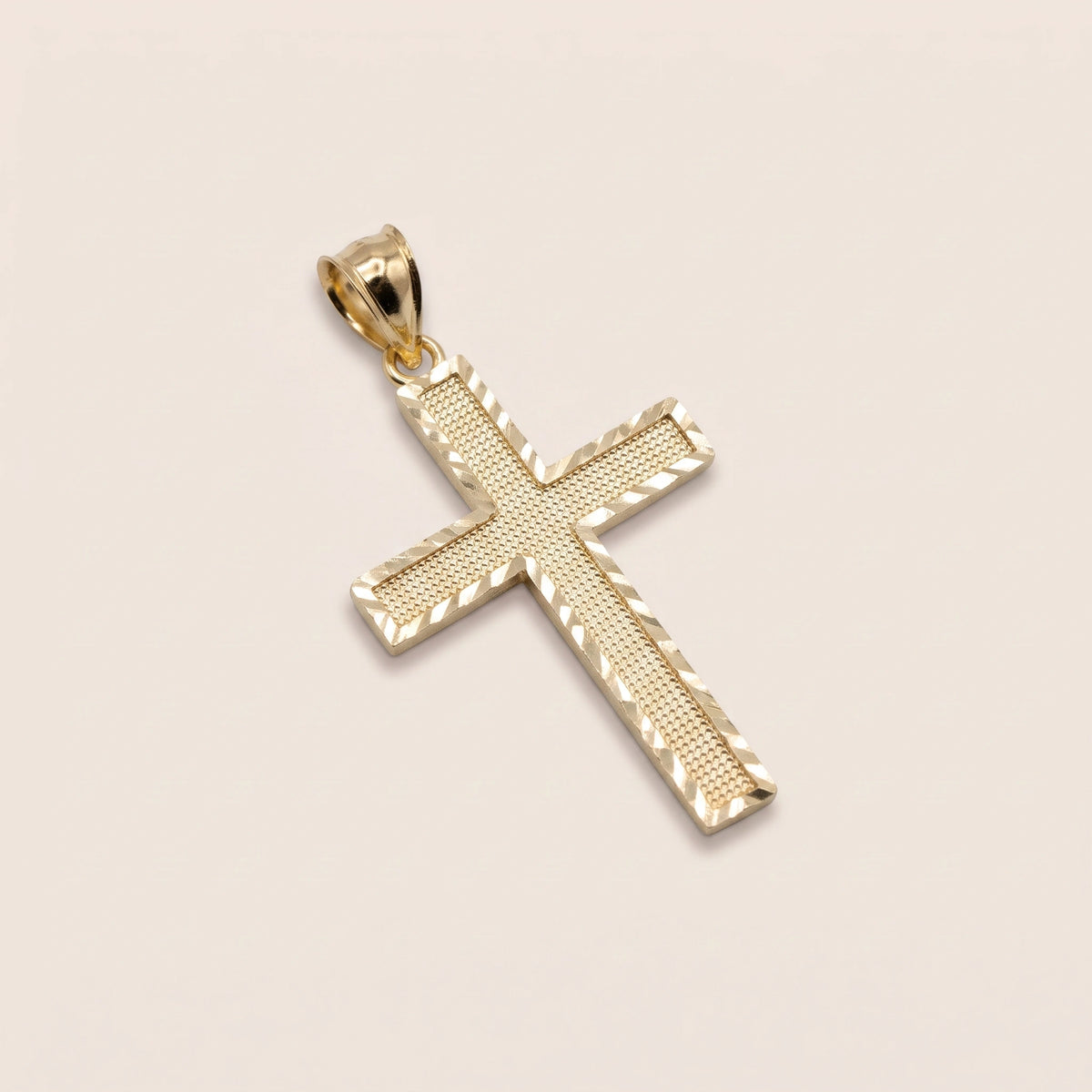 A 10k gold ribbed classic cross charm against a biege background.