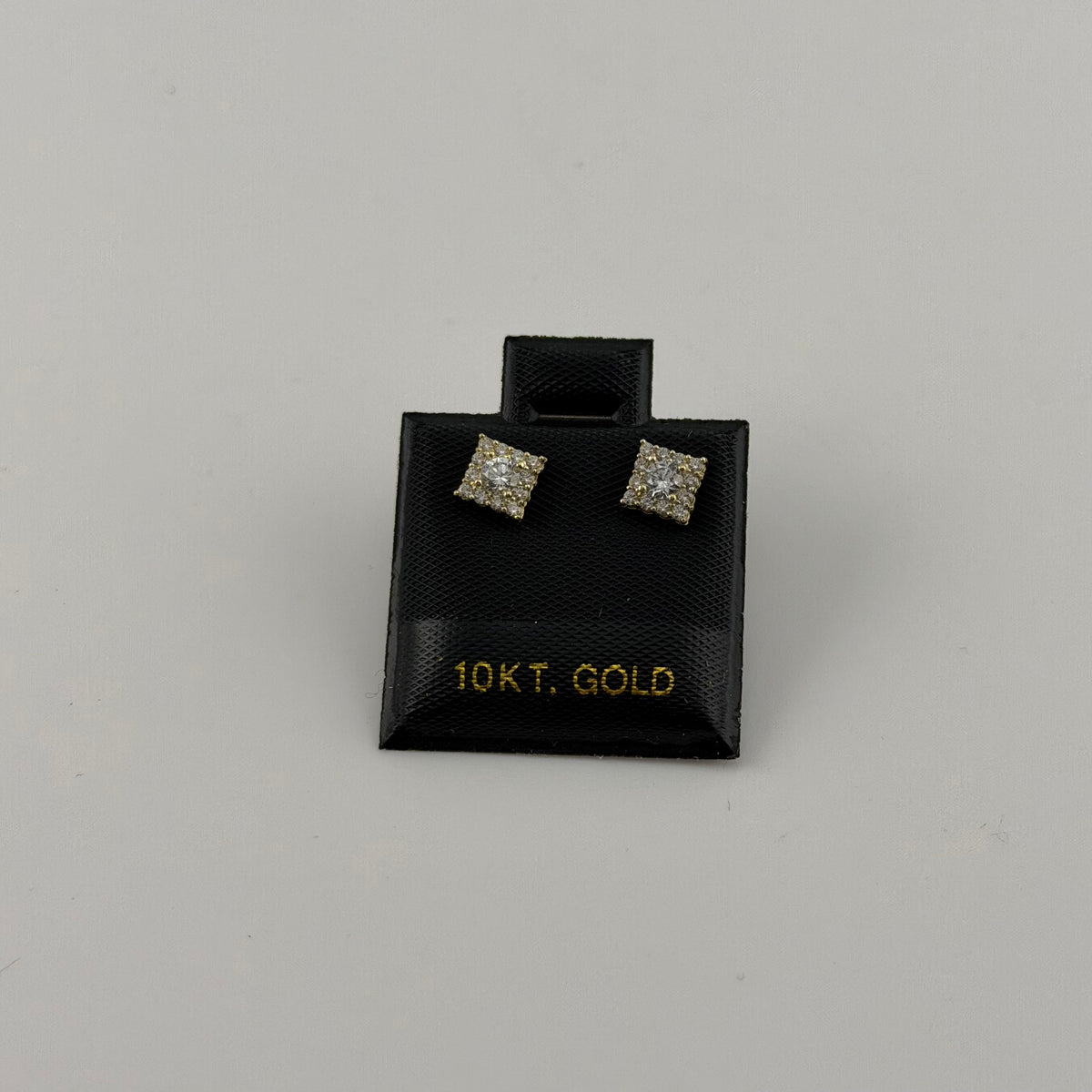 Pair of diamond stud earrings on a black 10kt gold jewelry box against a gray background