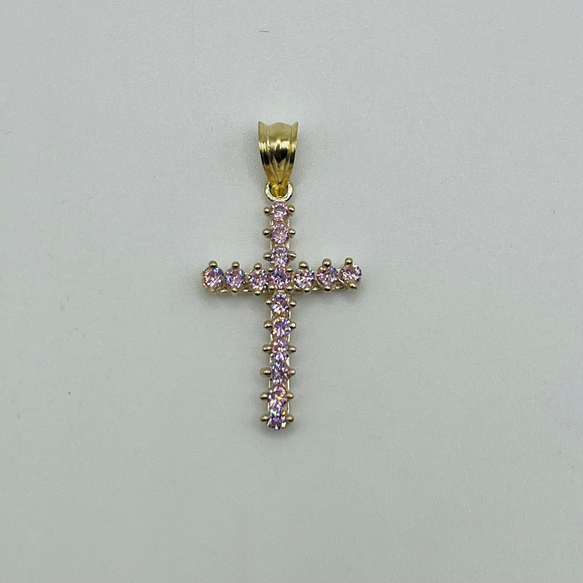 Gold cross pendant with pink gemstones on a light gray background