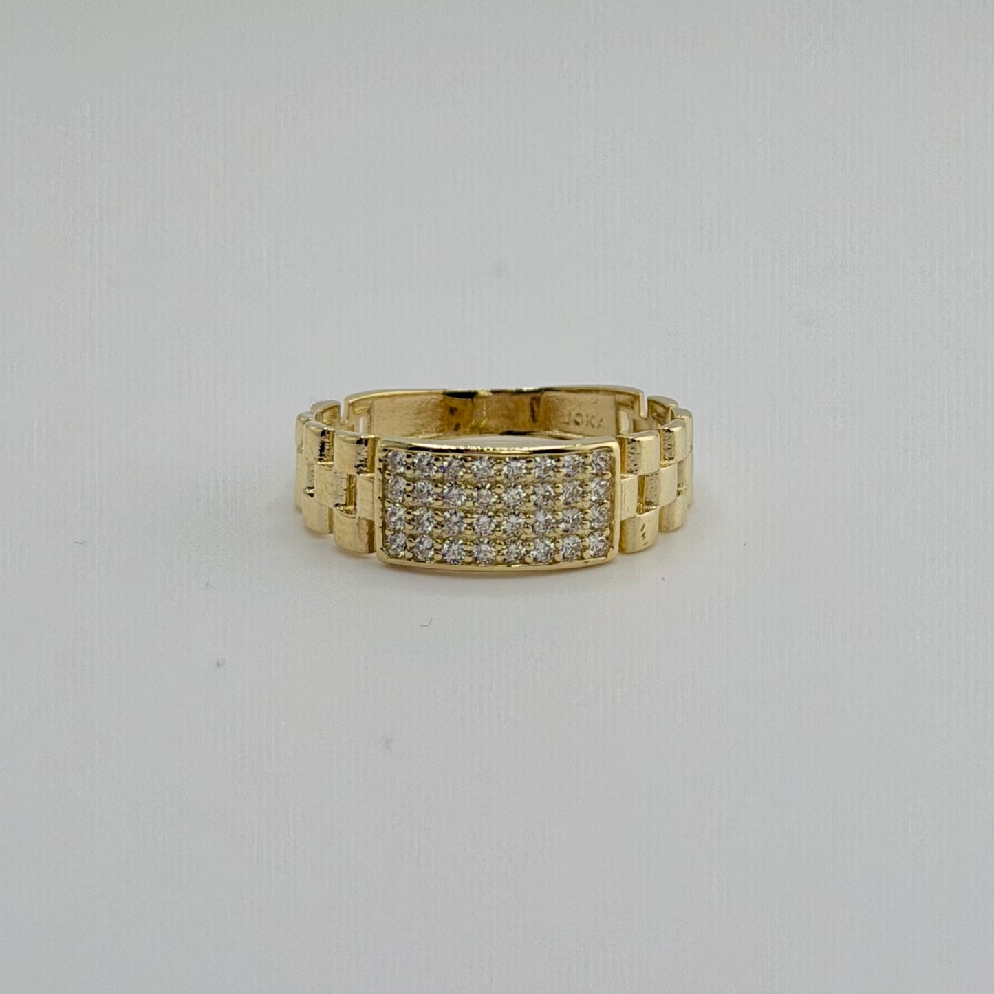 Gold ring with diamond accents on a light gray background