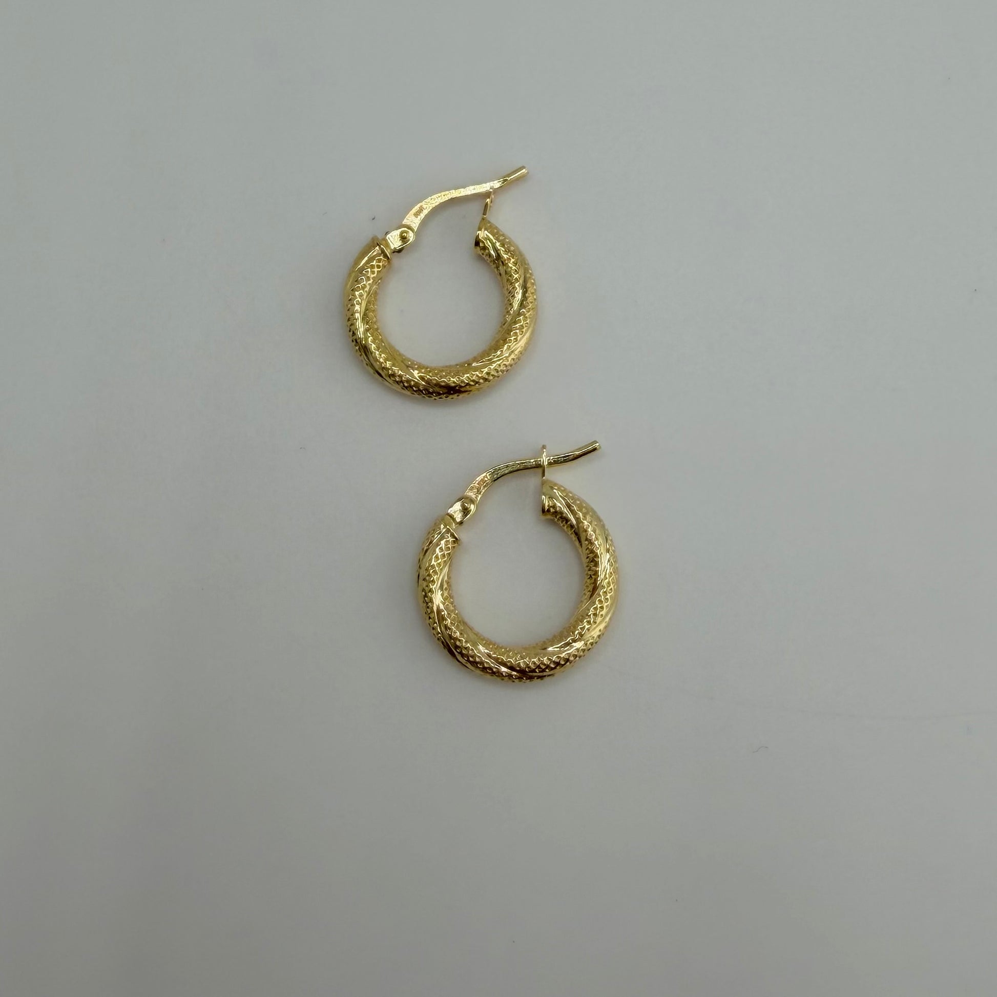 Gold hoop earrings on a gray background