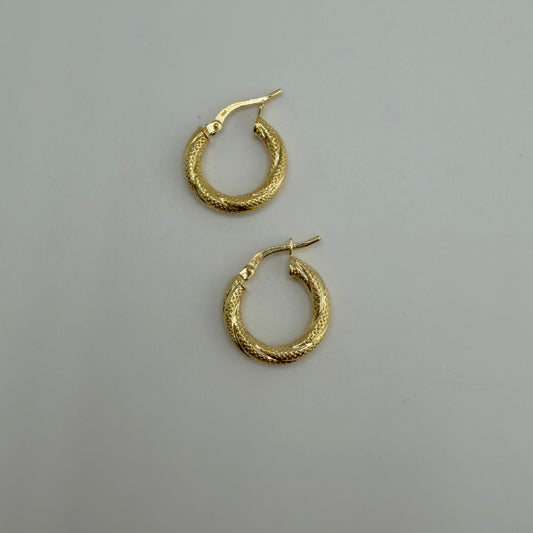 Gold hoop earrings on a gray background