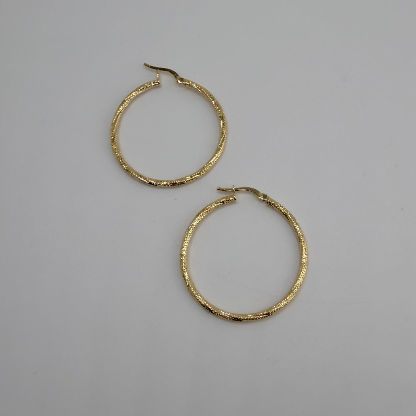 Gold hoop earrings on a gray background