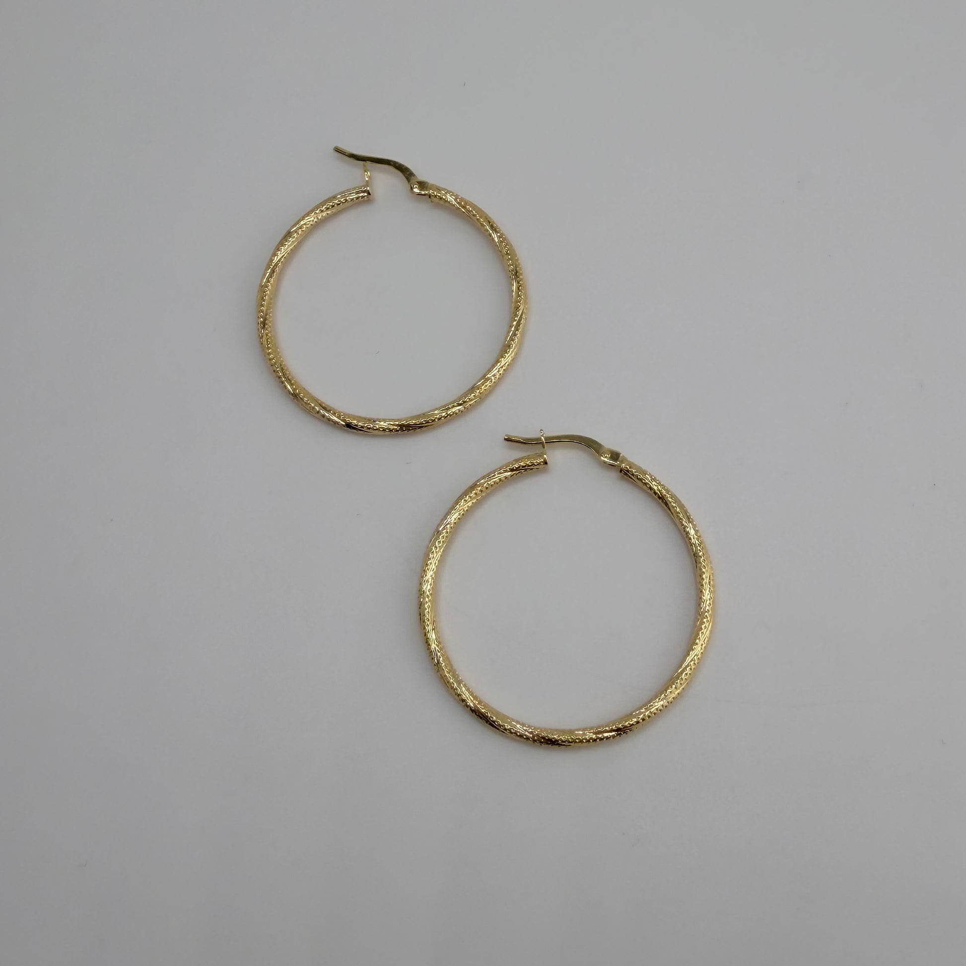 Gold hoop earrings on a gray background
