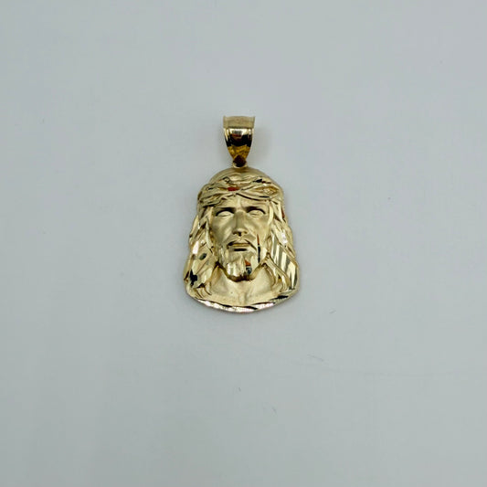 Gold pendant with a face design on a gray background