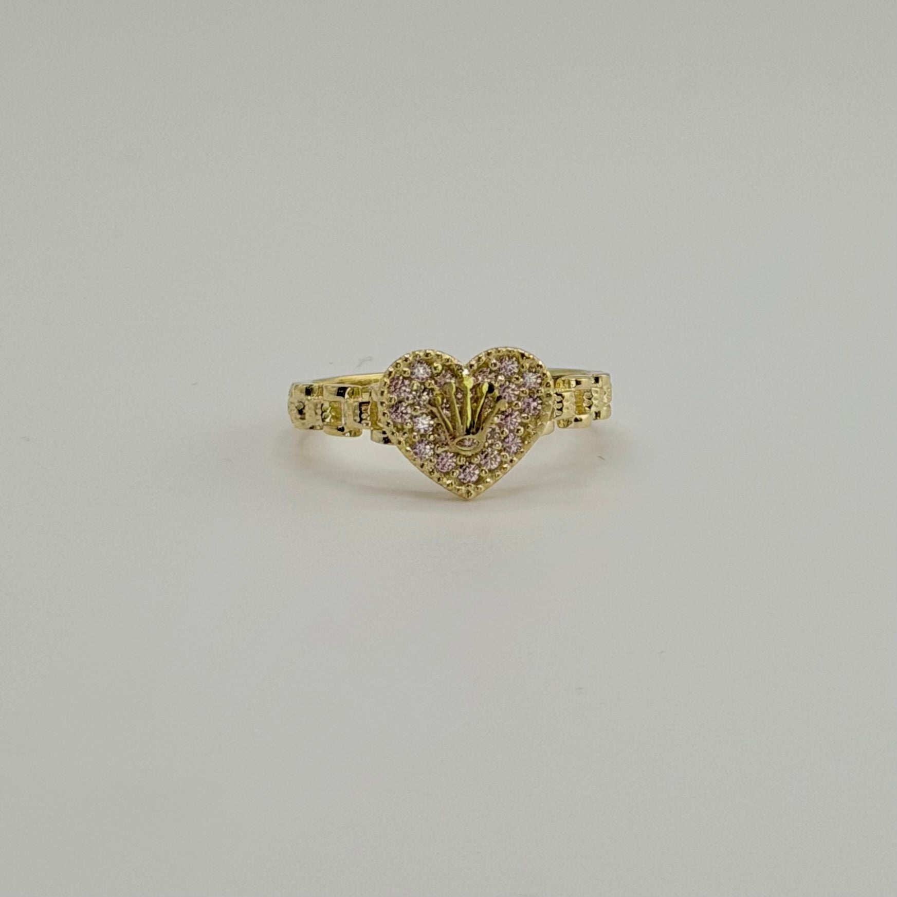 Gold heart-shaped ring with diamonds on a light gray background