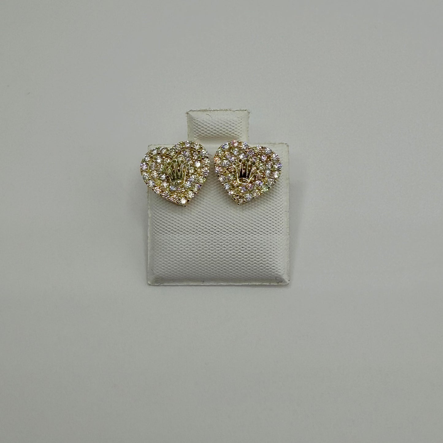 Heart-shaped earrings with rhinestones on a gray background