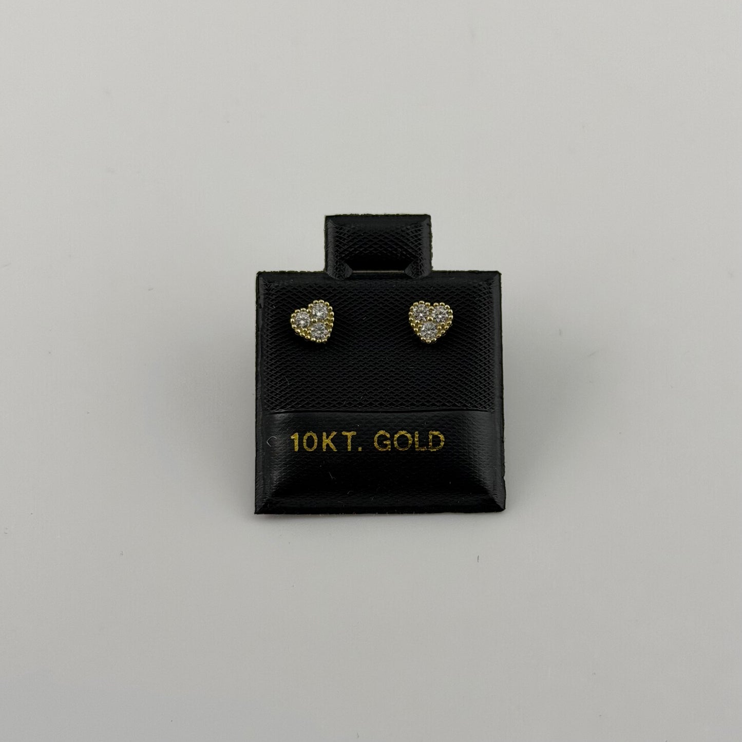 Pair of heart-shaped gold earrings in a black box labeled '10KT. GOLD' on a gray background