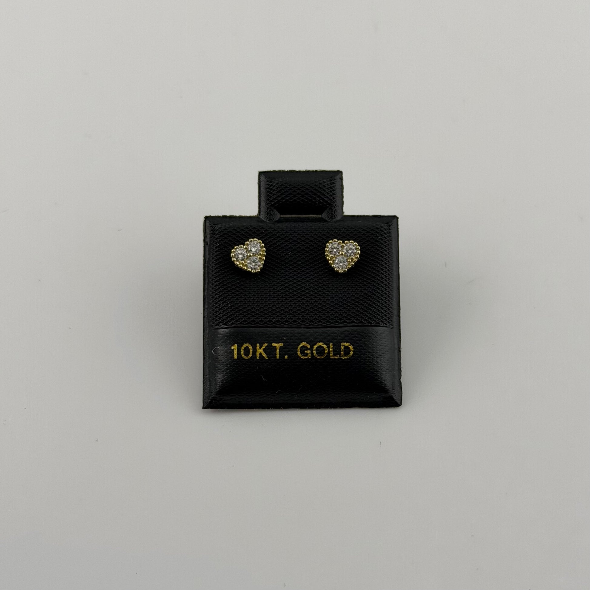 Pair of heart-shaped gold earrings in a black box labeled '10KT. GOLD' on a gray background