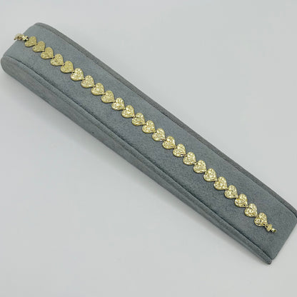 Gold bracelet on a gray cushion against a light gray background