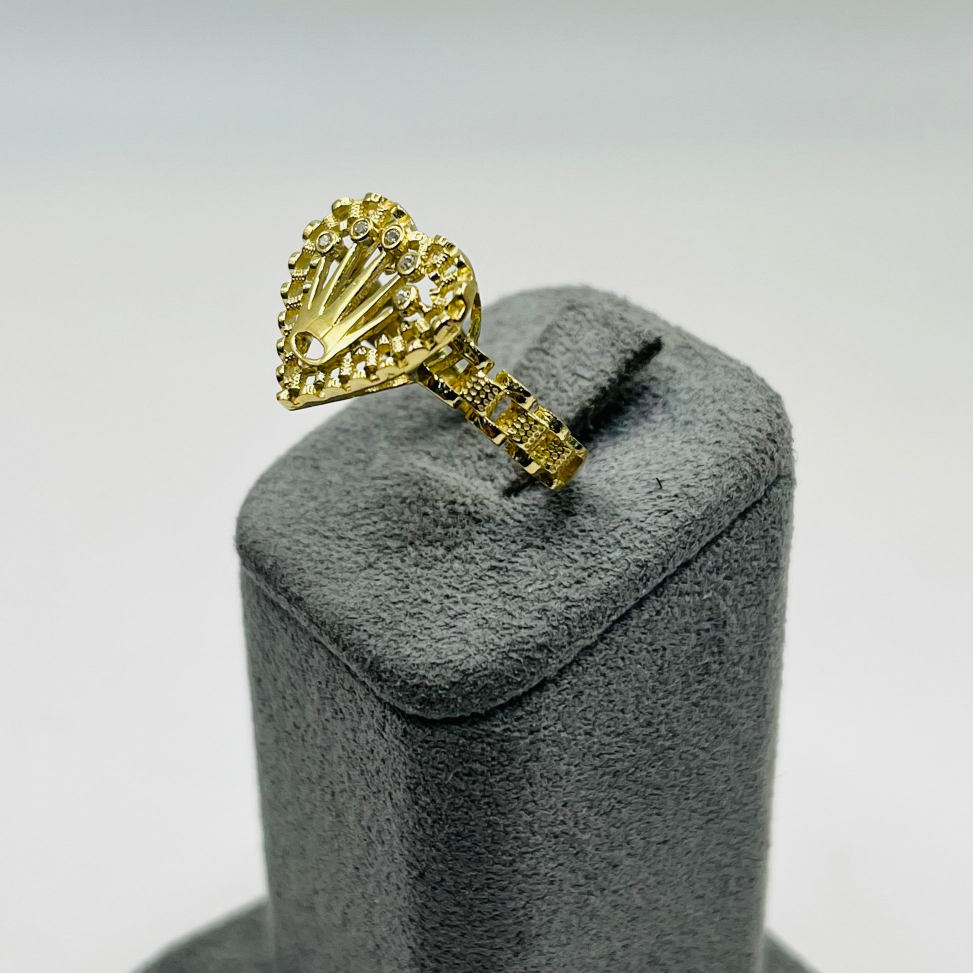 Gold ring on a gray velvet stand against a light gray background