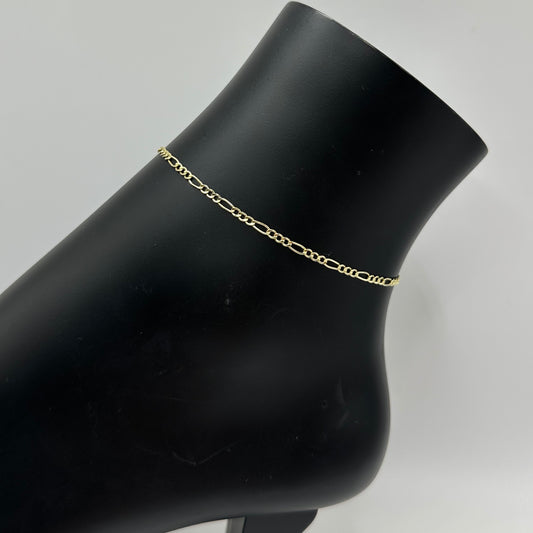 Gold chain bracelet on a black mannequin arm against a gray background