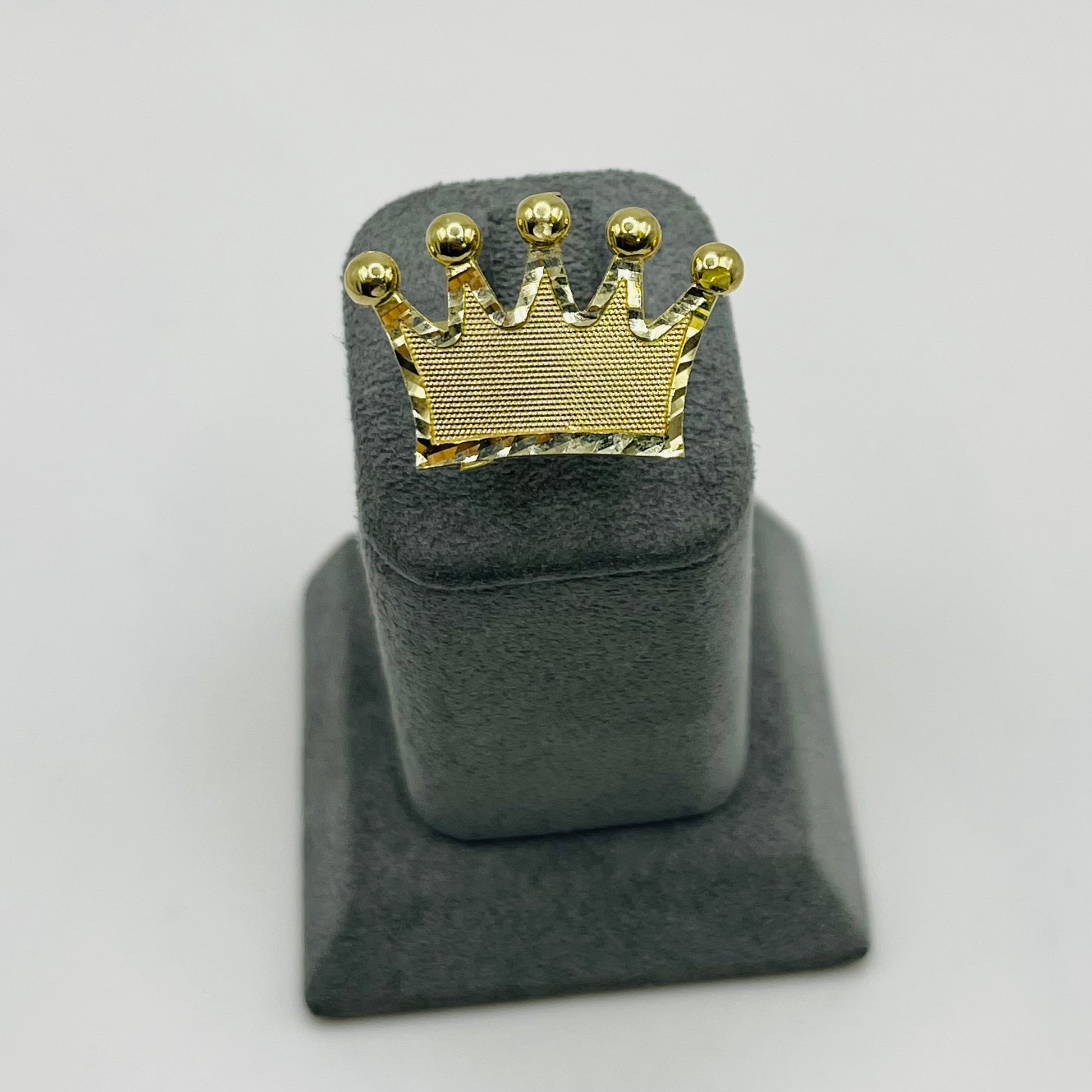 Gold crown-shaped object on a gray stand against a white background