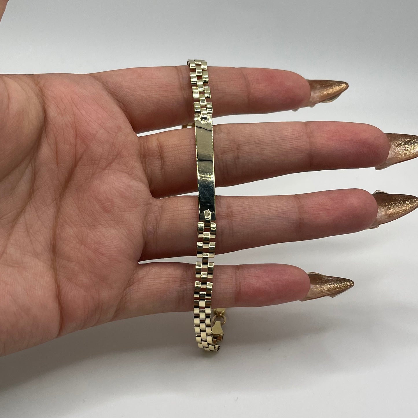 Gold bracelet on a person's wrist with a plain background